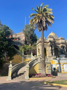 Elegant stone staircase and lush palm tree at Santa Lucía Hill in Santiago, Chile, under a clear blue sky.