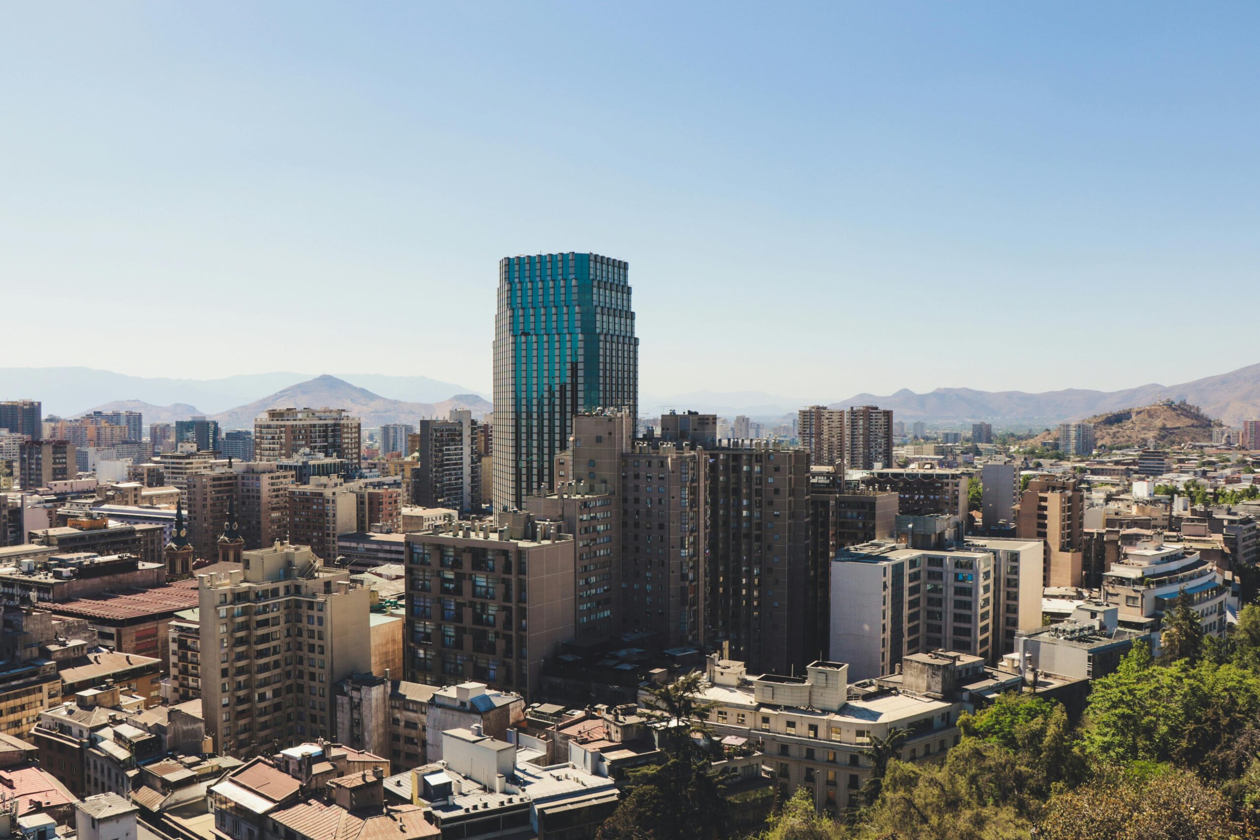 Stunning aerial shot of Santiago's modern skyline with mountains in the background during daytime.