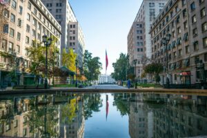 Picturesque urban scene of Santiago with a Chilean flag reflection in the plaza.
